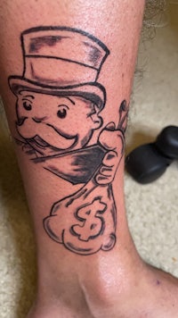 a tattoo of a man with a money bag on his leg